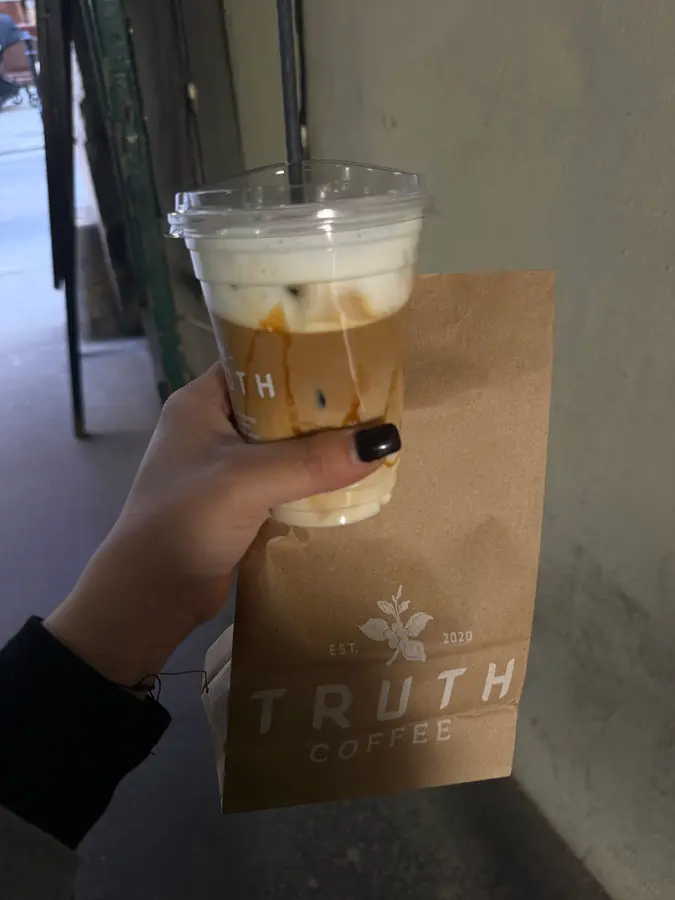 Iced Latte mit Karamell vor einer Papiertüte mit Truth-Coffee-Logo