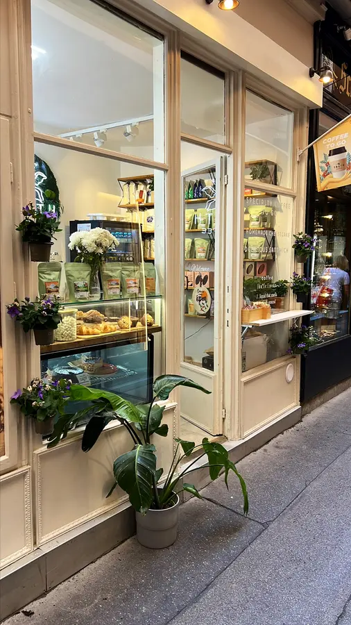 Eingang mit Glastür, Blumen und Grünpflanze, im Regal Kaffeepackungen